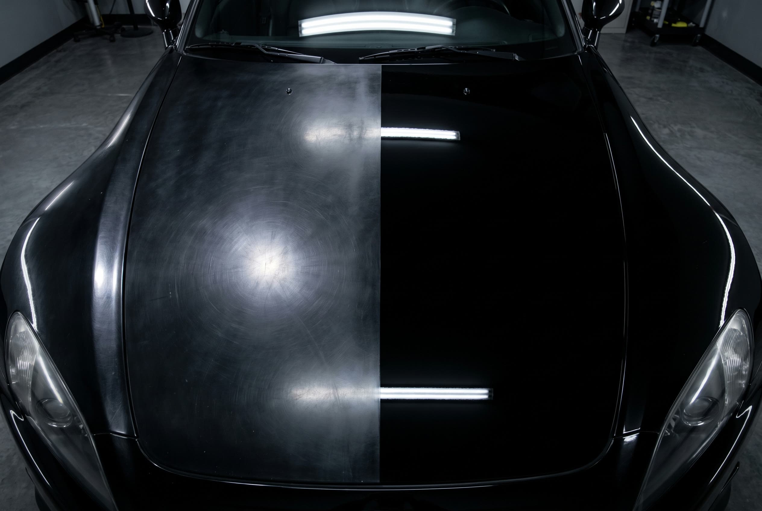 Black car hood split down the middle, dull and swirled on the left, mirror finish on the right