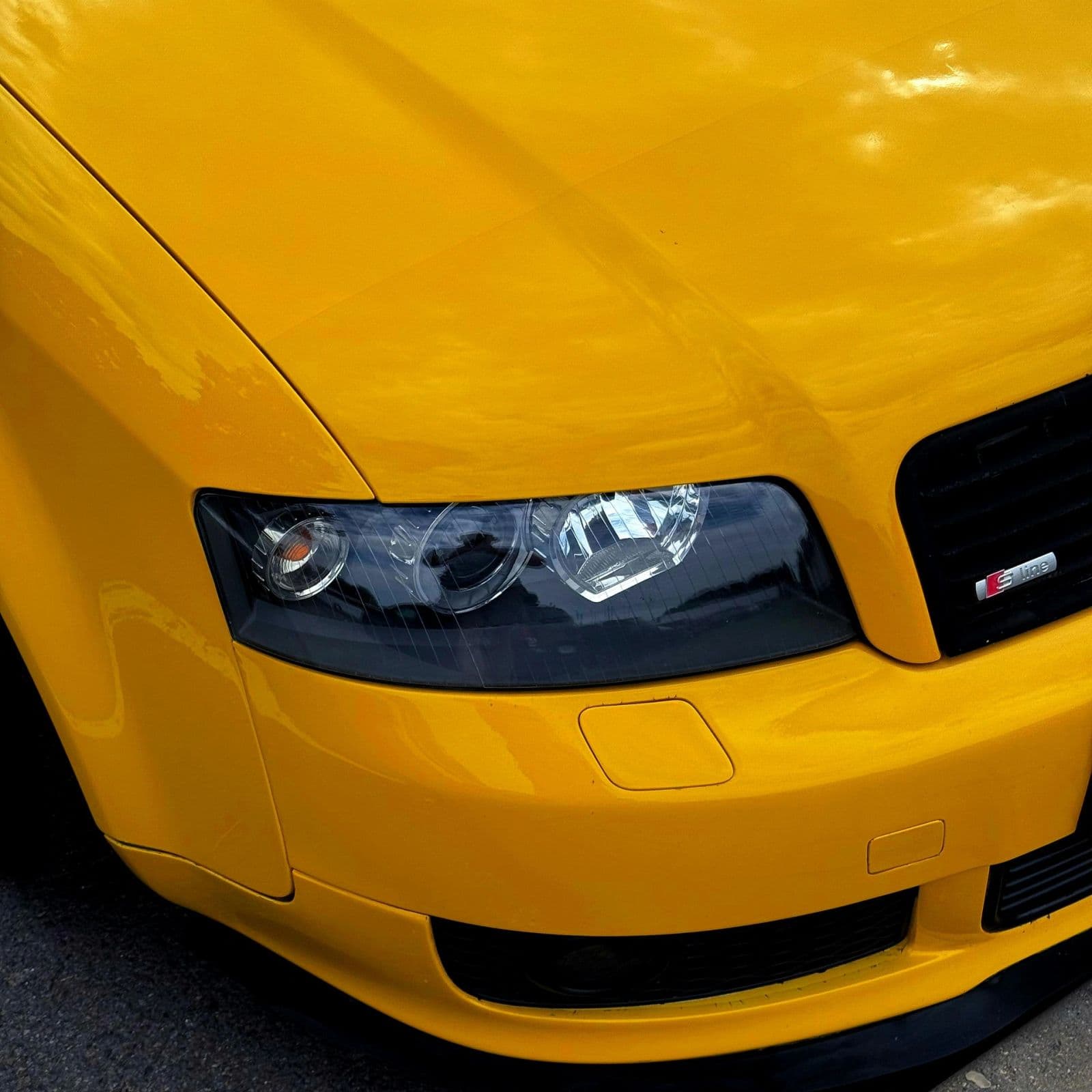 Front end of a bright yellow car cleaned and detailed